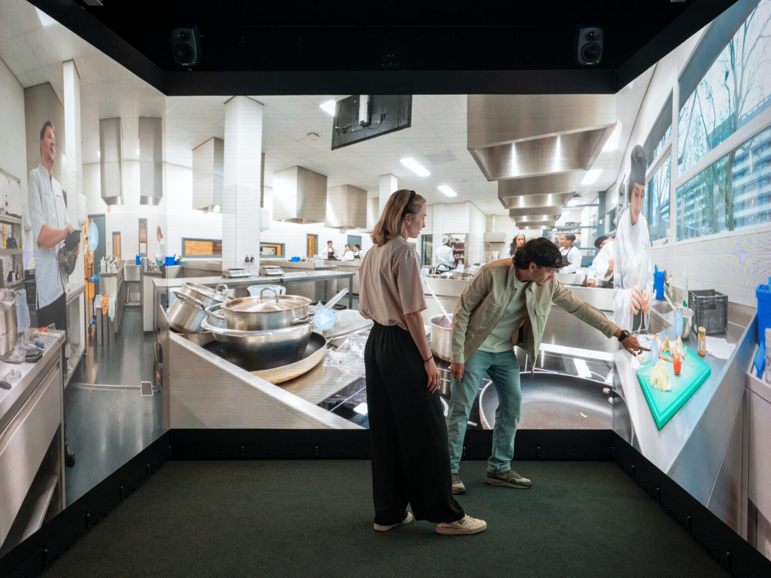Twee personen bekijken en bedienen een interactieve keukenomgeving in de Immersive Room van DO-IT PRO-AV.
